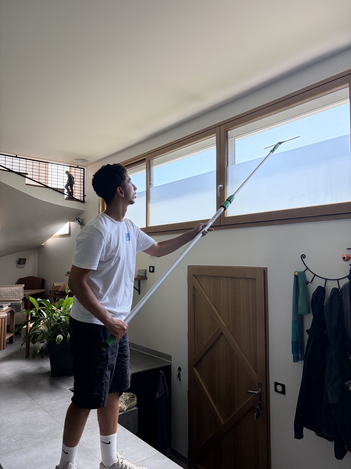 Mohamed Moussous nettoyant une baie en hauteur avec sa perche télescopique